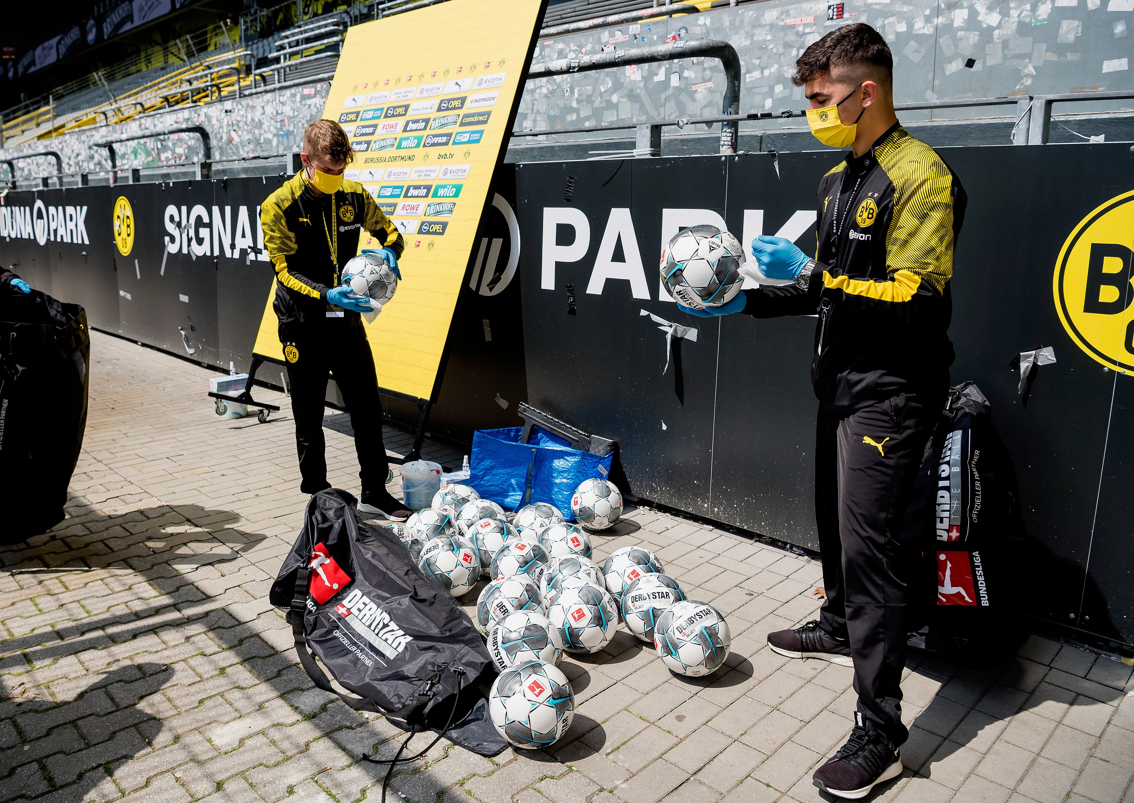 Funcionários do Borussia Dortmund trabalham na higienização das bolas que serão usadas na partida contra o Schalke 04