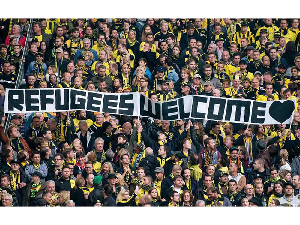 Torcida do Borussia Dortmund com faixa “Bem-vindos, refugiados”