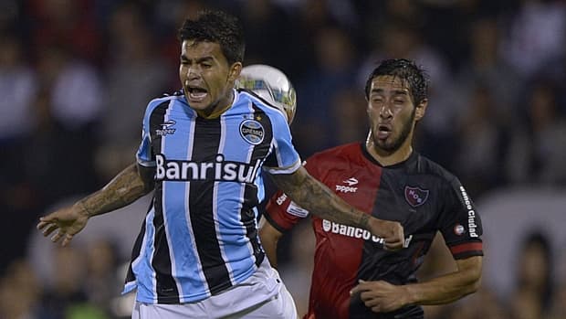 O gremista Dudu disputa a bola com Victor Lopez, do Newell's