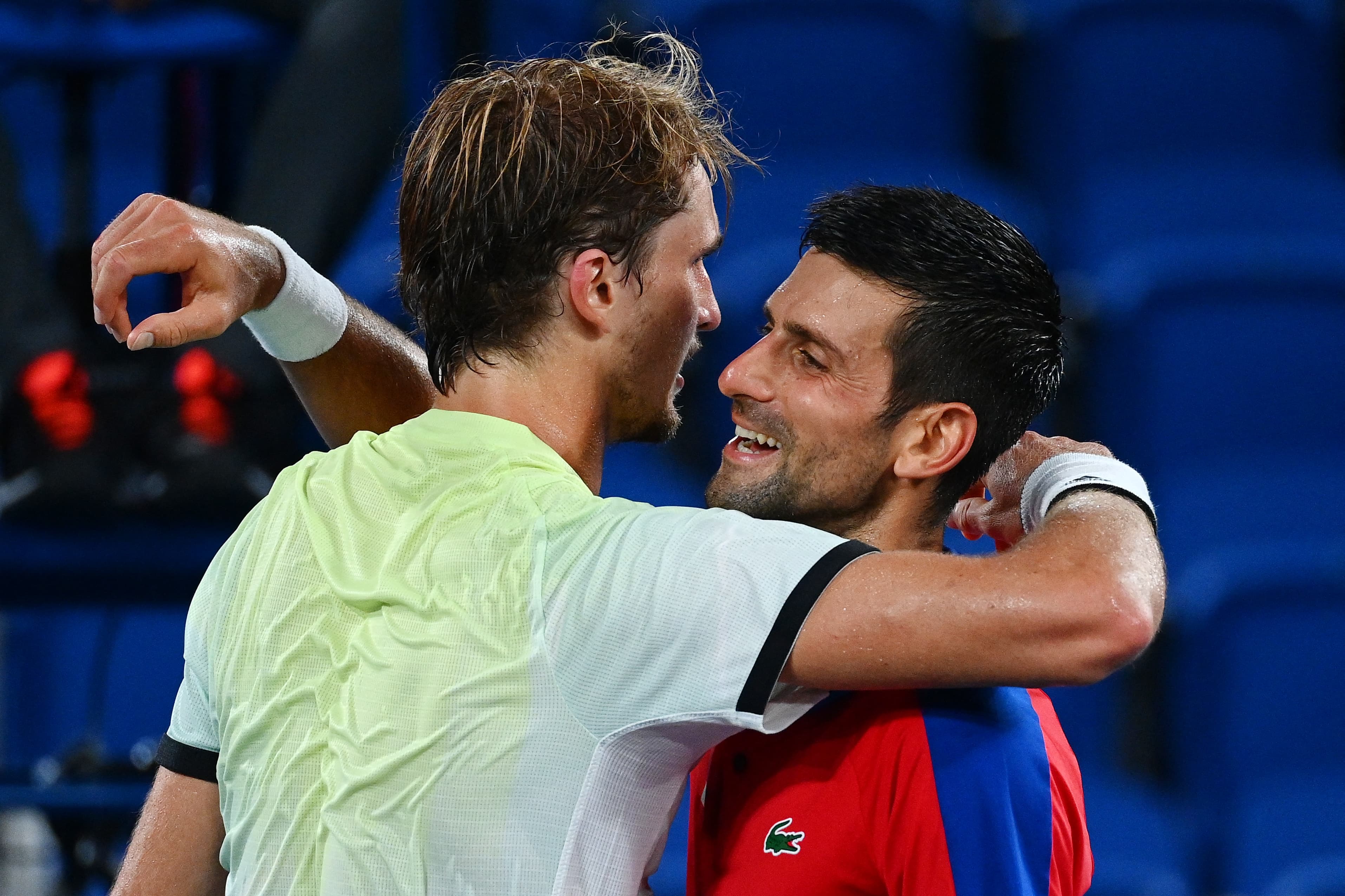 Serbia's Novak Djokovic (R) congratulates Germany's Alexander Zverev for winning their Tokyo 2020 Olympic Games men's singles semifinal tennis match at the Ariake Tennis Park in Tokyo on July 30, 2021. (Photo by Vincenzo PINTO / AFP)
