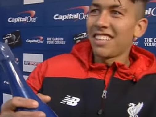 Roberto Firmino tenta devolver champanhe que recebeu como melhor jogador da partida