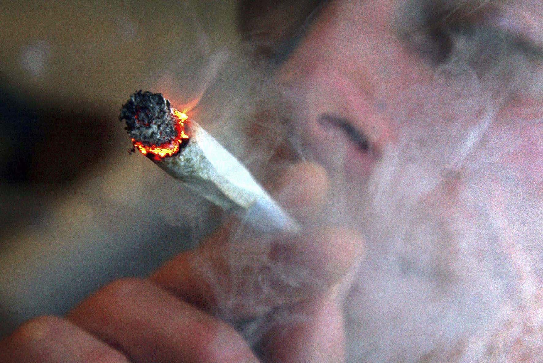 Homem acende cigarro de maconha