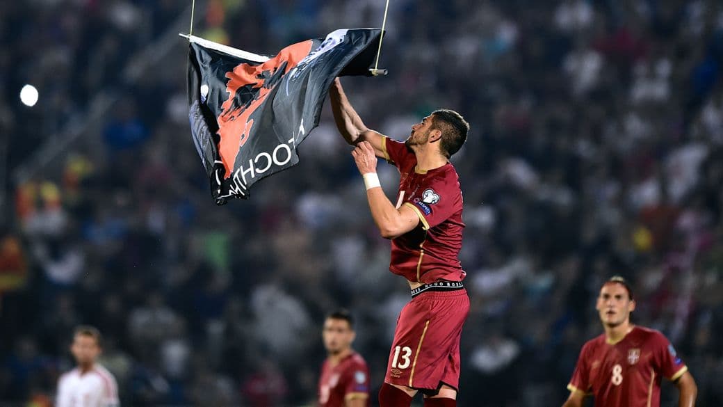 O meia sérvio Mitrovic agarra a bandeira albanesa carregada por um drone no jogo válido pelas Eliminatórias da Eurocopa, em Belgrado