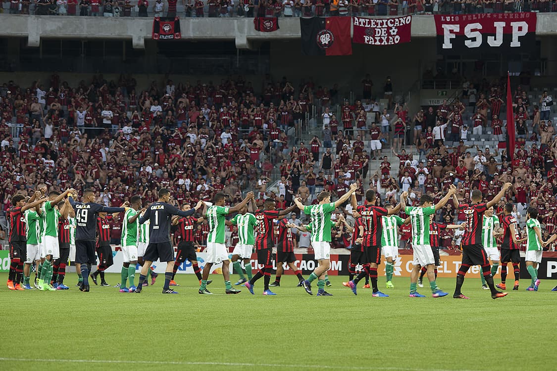 Equipes do Atlético PR e Coritiba de mãos dadas no gramado, sinalizam o cancelamento do jogo na Arena da Baixada, em Curitiba