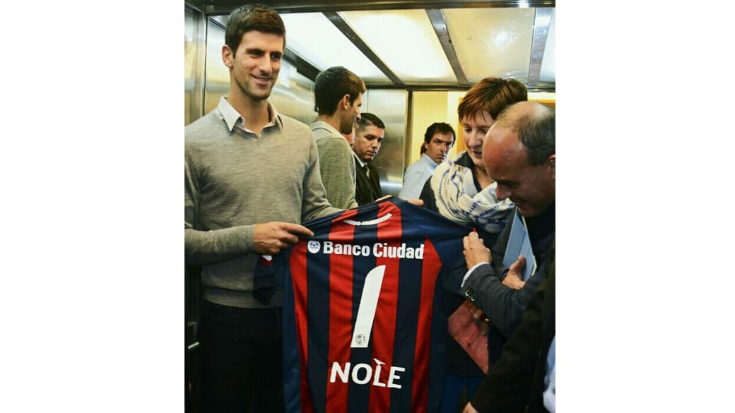 Novak Djokovic recebe a camisa do time argentino Clube Atlético San Lorenzo durante visita a uma escola estadual na cidade de Buenos Aires