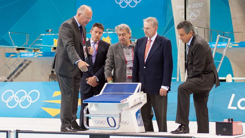 Sebastian Coe, do Locog, Jacques Rogge, do COi, e executivos da Omega examinam o novo bloco de largada na piscina do Centro Aquático do Parque Olímpico de Londres