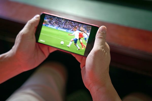 Man watching football and sport stream on mobile phone.