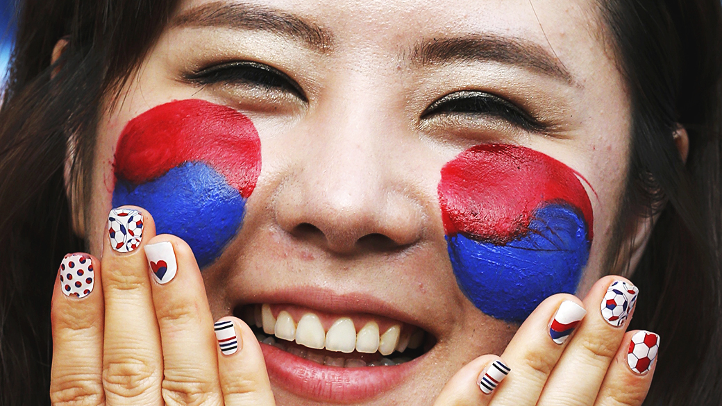 Torcedora pinta a bandeira da Coreia do Sul no rosto para partida contra a Rússia na Arena Pantanal, em Cuiabá
